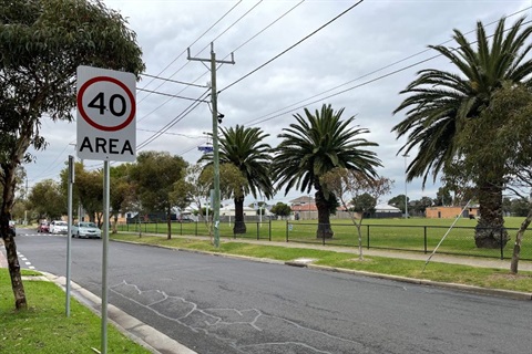 An empty tree lined road with a 40km per hour traffic speed sign in the foreground